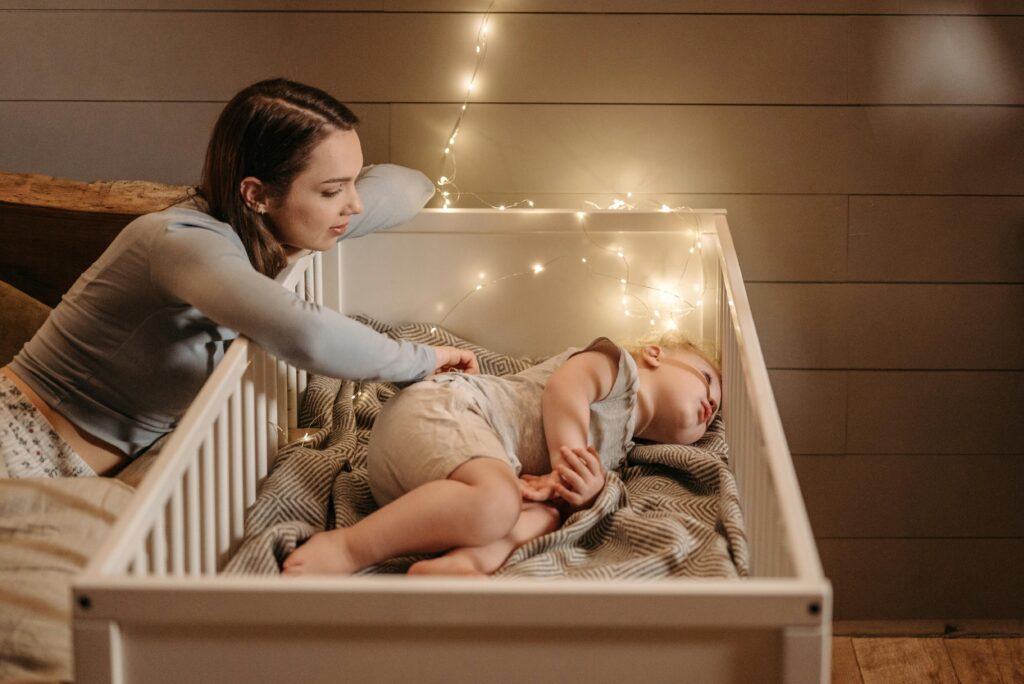 A tender moment of a mother watching over her sleeping baby in a warmly lit bedroom.