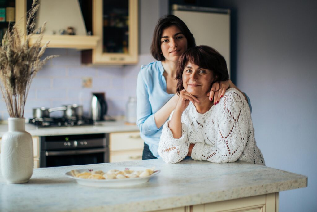 A loving moment shared between mother and daughter in a cozy kitchen, depicting warmth and bonding.