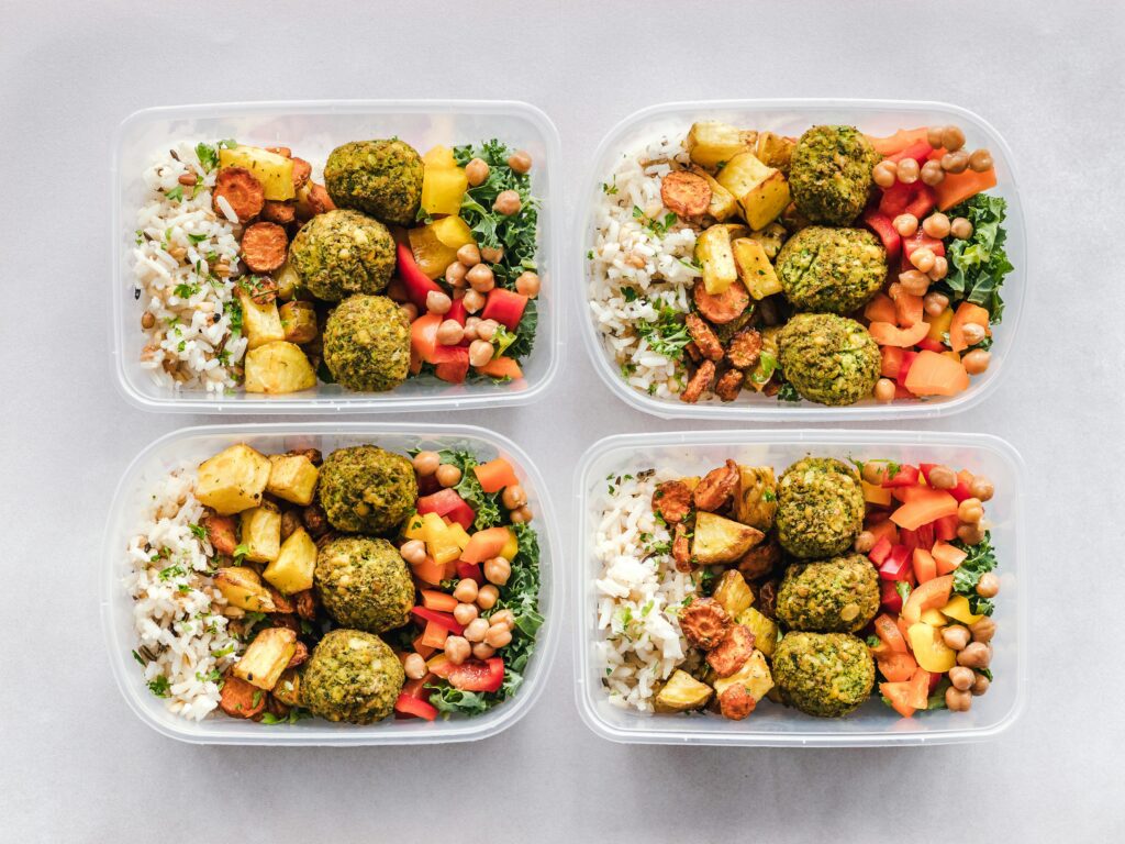 다이어트 정체기 탈출 루틴 Colorful meal prep containers with falafel, chickpeas, rice, and vegetables for a healthy lifestyle.