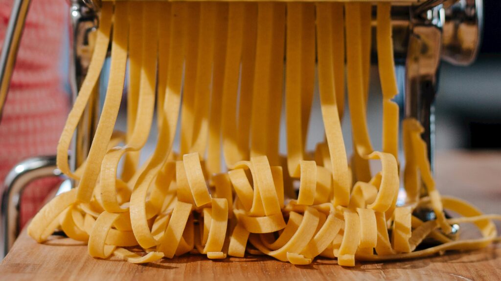 ํ์คํ๐ ๋ค์ด์ดํธ, 40๋๋ ์ด ์์ฐ๊ฒ ๋จน๋ ๋ฐฉ๋ฒ! Close-up of fresh pasta strands being made with a pasta machine in an indoor kitchen setting.