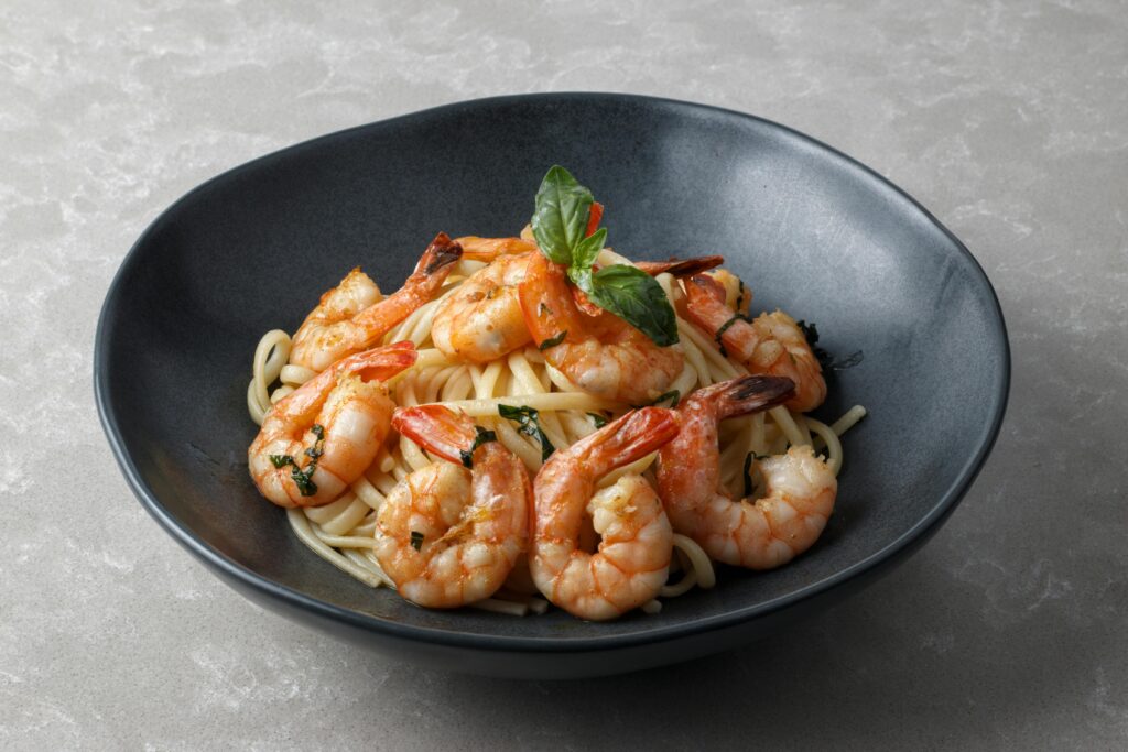 ํ์คํ๐ ๋ค์ด์ดํธ, 40๋๋ ์ด ์์ฐ๊ฒ ๋จน๋ ๋ฐฉ๋ฒ! A tantalizing dish of shrimp pasta garnished with fresh herbs in a dark ceramic bowl.